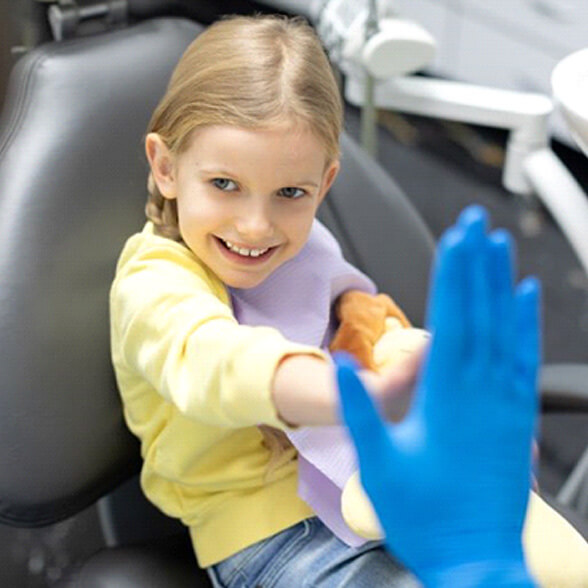 Smiling young girl giving high-five to dental team member