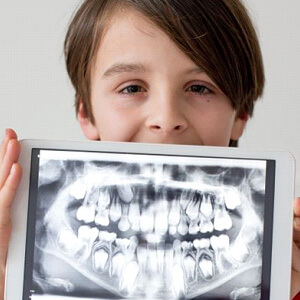 Child holding tablet that is displaying dental x-ray