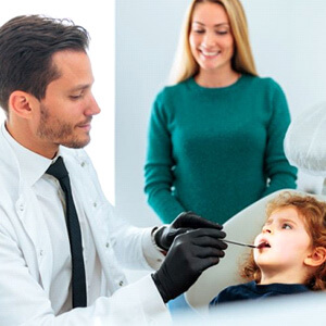 Mom smiling while dentist examines her child