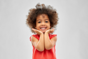 Little girl smiling with a full set of teeth on white background